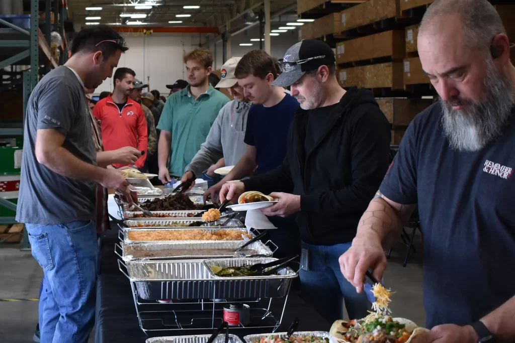 Employees scooping food onto plate at cookout