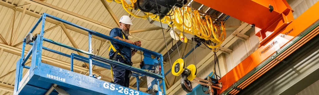 Patrick fixes a crane standing on a scissor lift