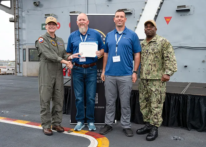 Eric Grace and Corey Mosher accept the NERE award aboard the USS Abraham Lincoln