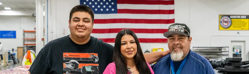 The family poses in front of an American flag with Juan on the left, Karissa in the middle and Tony on the right.
