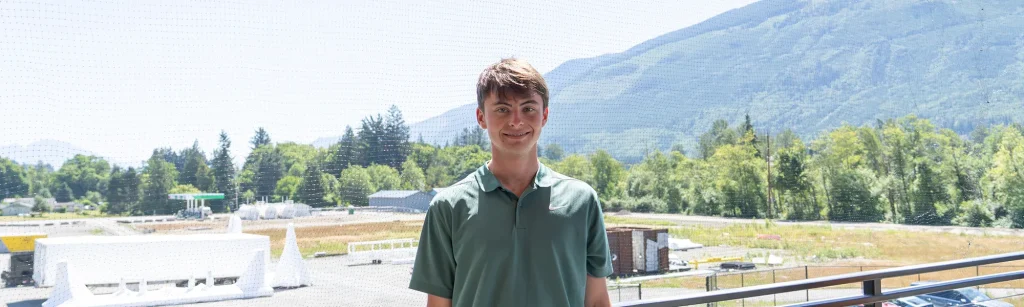 Ethan, production intern, posing with mountains in the background