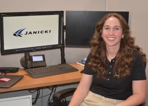 Janie sitting at a computer with Janicki logo on the screen