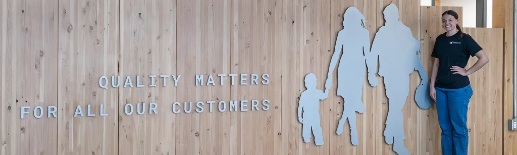 Jordyn standing in front of a sign that reads "Quality Matters For All Our Customers"