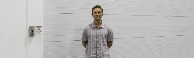 Luke, NDI engineering intern, poses in front of a garage door