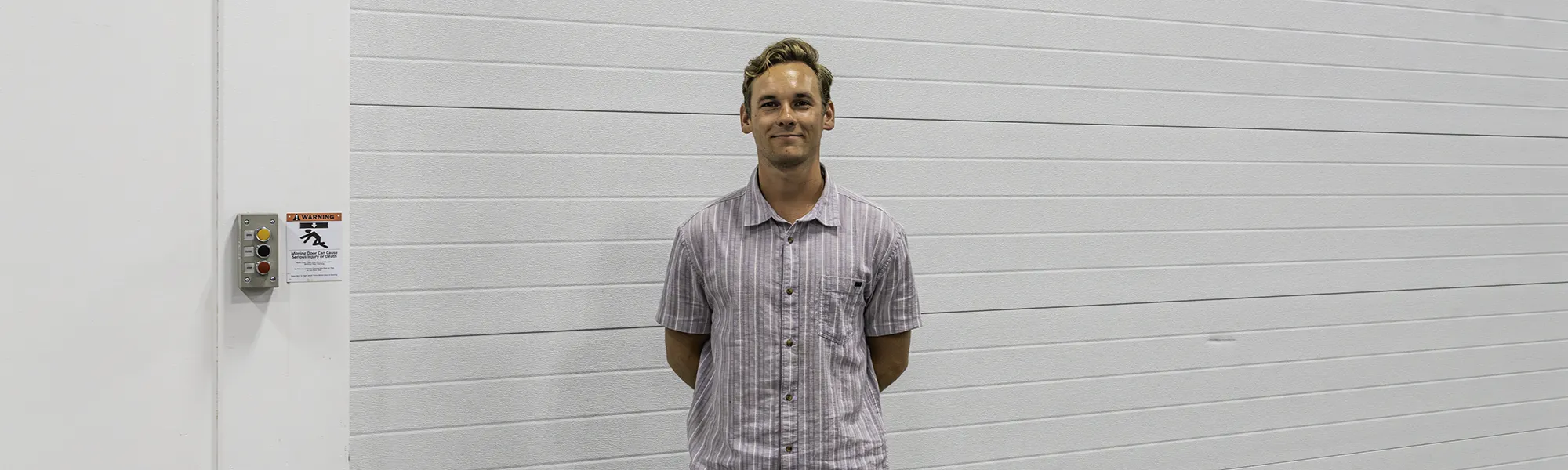Luke, NDI engineering intern, poses in front of a garage door