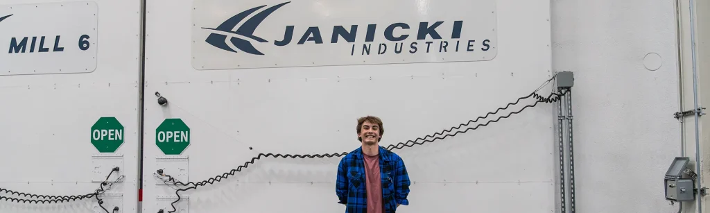 Hunter, an engineering intern from Montana State University, poses in front of a Janicki mill door