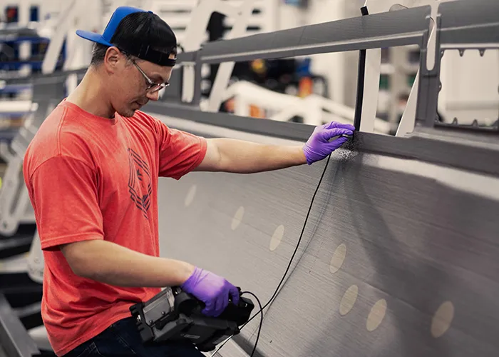 An employee uses a non destructive inspection scanner on a composite panel