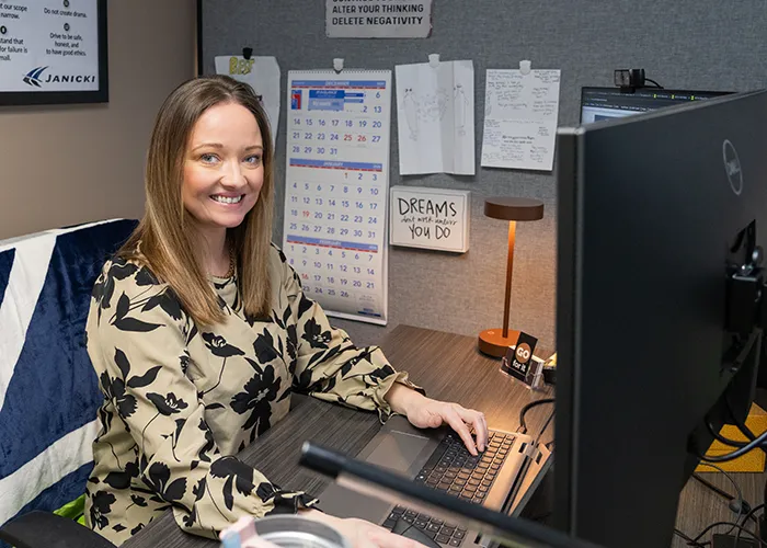 Rebecca, Janicki HRIS Analyst, smiles while sitting at her desk
