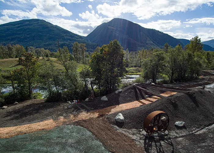 Walking trail through the Janicki campus park with mountain views, sculptures and company buildings in the background.
