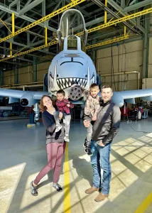 Tye poses with his wife and two boys for a photo in front of the nose of an A-10 airplane