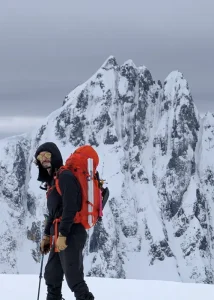 Elias with backpack and ski gear on mountain with snow